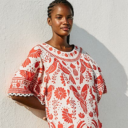 A woman in a red and white patterned FARM Rio dress.